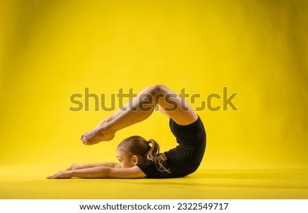 gymnast in a black leotard on a yellow background. flexible girl goes in for sports. isolate