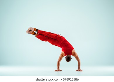 The gymnastic acrobatic caucasian man posing in balance posture on gray studio background