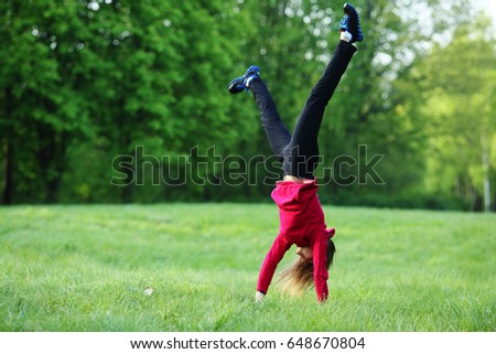 Gymnastics woman exercising handstand sport outdoor, green park, grass, full lenght, natural green background