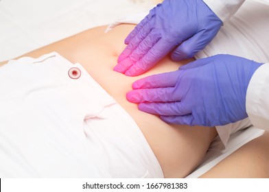 A Gynecologist Doctor Probes The Lower Abdomen Of A Girl Who Has Pain And Inflammation Of The Reproductive System. Ovarian Cyst, Endometriosis, Pregnancy Pathology