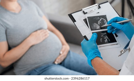 Gynecologist looks at an ultrasound of a pregnant woman.  - Powered by Shutterstock