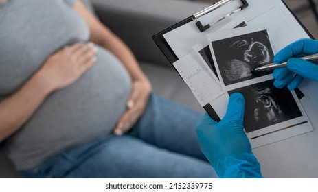 Gynecologist looks at an ultrasound of a pregnant woman.  - Powered by Shutterstock