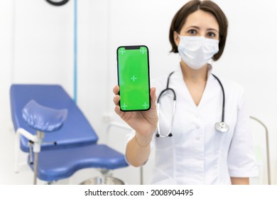  Gynecologist Shows An IPhone 12 With A Chromakey. The Doctor In The Gynecological Office Shows Mobile Phone With Green Mock Up Screen. Online Consultation With Doctor .June 16, 2021 - Moscow, Russia 