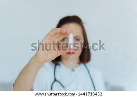 gynecologist with swab in his hand. Woman doctor shows tampon.
