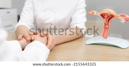 Gynecologist woman hold hand of young female patient during medical consultation in modern clinic. Model reproductive system.