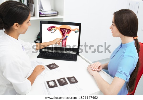 Gynecology, consultation. Gynecologist explains to\
a woman about a disease of the uterus, showing an endometrial polyp\
on her laptop