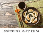 Gyoza or Japanese dumplings snack with soy sauce closeup on the plate on the table. Horizontal top view from above