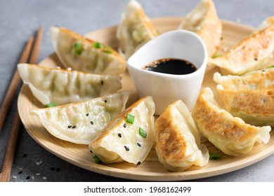 Gyoza or jiaozi fried stuffed dumplings on a bamboo plate, closeup view