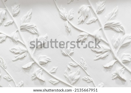 Gypsum plaster floral ornament. Decoration for the wall. White wall with floral ornament