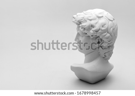 Gypsum statue of David's head. Michelangelo's David statue plaster copy on grey background with copyspace for text. Ancient greek sculpture, statue of hero