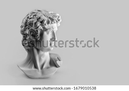 Gypsum statue of David's head. Michelangelo's David statue plaster copy on grey background with copyspace for text. Ancient greek sculpture, statue of hero