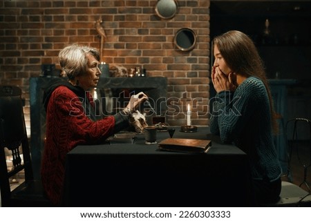 Gypsy witch reading tarot cards for young woman visitor
