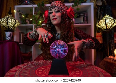 Gypsy Woman Loooking At Camera With A Magic Crystal Ball Around Her Hands With Rays Inside 