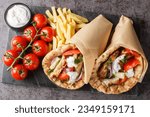 Gyros souvlaki wrapped in a pita bread closeup on the board on the table. Horizontal top view from above
