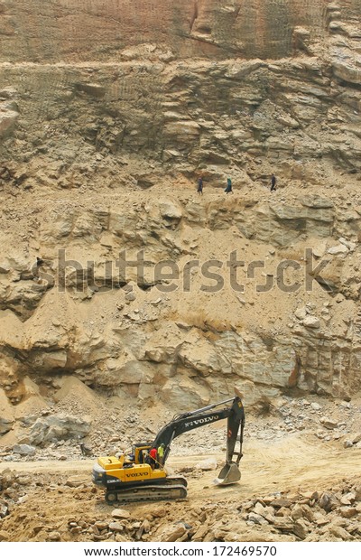 HA GIANG, VIETNAM - SEPT 4: An\
excavator working on a mountain and local minority residents\
walking above on September 4, 2010 in Ha Giang province,\
Vietnam.