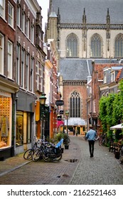 Haarlem, Holland, May 23, 2022: Single man walking alone down Warmoesstraat shopping street in Haarlem.  Grote Kerk church in the background.