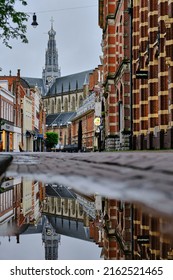 Haarlem, Holland, May 23, 2022: Low angle view of an empty shopping street Zijlstraat in Haarlem.  Grote Kerk church in the background. Reflections in puddle.