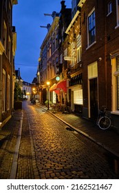 Haarlem, Holland, May 23, 2022: Empoty side-street Warmoesstraat in Haarlem at night time.  Light reflections on the cobblestones.
