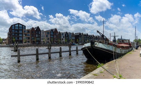 Haarlem, Netherlands - 21 May, 2021: row of colorful houses on the canals of Haarlem with an old river boat barge in the foreground