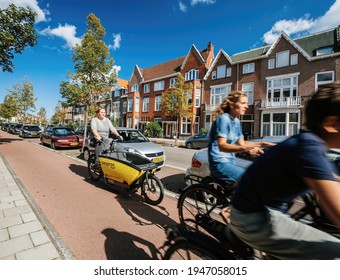 Haarlem, Netherlands - Aug 17, 2019: People riding bikes on Haarlem street with woman riding yellow shared Cargoroo e-cargo bike elektrische buurtbakfiets - fast commuting on Dutch street