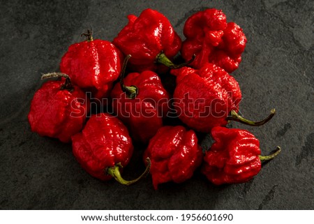 Habanero peppers on dark background, ripe red on rustic table, hot spicy habanero peppers