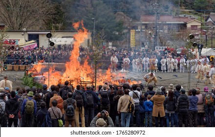 Hachioji, Tokyo / Japan - March 10 2019: A large crowd watches monks use water buckets to control the central bonfire at the annual fire-walking festival near Mount Takao, west of Tokyo