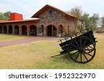 Hacienda colonnial country house, stone construction arches and wooden cart on the lawn