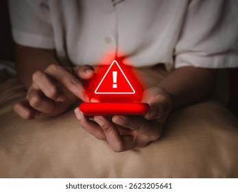 Hacker attack detection alert, sms fraud and scammer calls, fraudulent phone calls concept. Red triangle warning caution alert show on smart mobile phone in senior elderly hands, in the dark room.