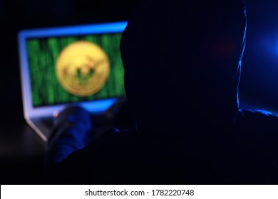 Hacker with computer hacking and stealing data information, Selective focus image on hacker's hoodie, Bitcoin logo and binary code as background. Bitcoin cryptocurrency security and privacy issues.