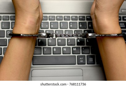 Hacker concept, punishment for cybercrime with one person in handcuffs above notebook keyboard