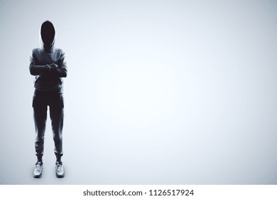 hacker with crossing hands in sport suit at light background.