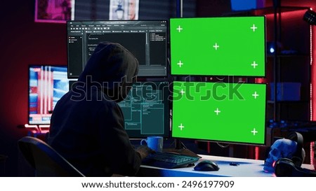Hacker developing spyware software on green screen computer to steal important data to be sold on black market. Hooded scammer writing malicious code on chroma key PC, camera A