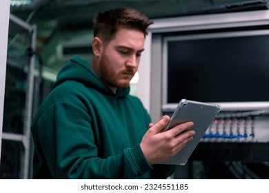 Hacker or engineer in data center holding tablet steals software checks information from server cloud storage technologies