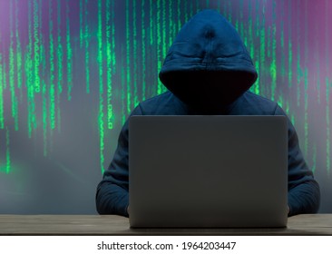 The hacker is in front of his computer. Cybersecurity, hoodie. Dark face Digital figures in the background
