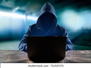 Hacker in front of his computer. Dark face. Blurred background