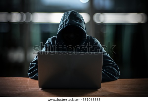 Hacker in front of\
his computer. Dark face