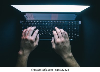 The hacker hacks the server with bank accounts in a dark room on a black background in the dark. 