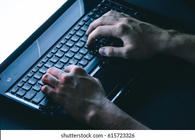 The hacker hacks the server with bank accounts in a dark room on a black background in the dark. 
