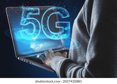Hacker hands using notebook with creative glowing polygonal 5G hologram on blue background. Internet speed, hacking, theft, connection and service concept