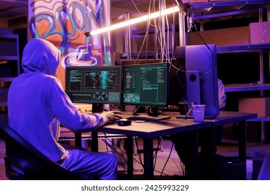 Hacker in hood gathering information using illegal spyware on computer to break into server. Criminal doing web tracking with malicious software and checking data on screen