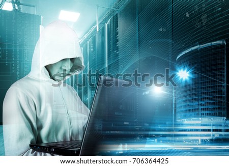 hacker in hood with a laptop in hand on background of rows of servers, data center and skyscrapers of the city at night