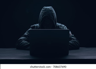 hacker in a hood on a dark background, IT specialist                               