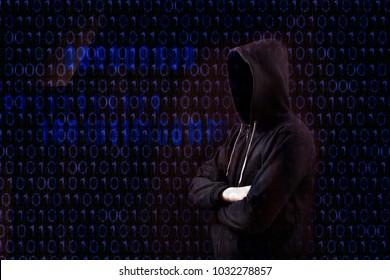  hacker with a hood over a screen with binary code