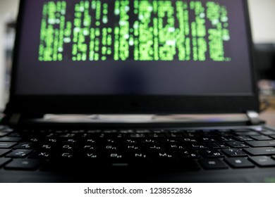 a hacker with a hood over a screen with binary code