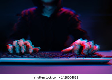 Hacker in the hood working with computer typing text in dark room. Image with glitch effect