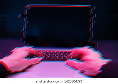 Hacker in the hood working with laptop typing text in dark room. Image with glitch effect
