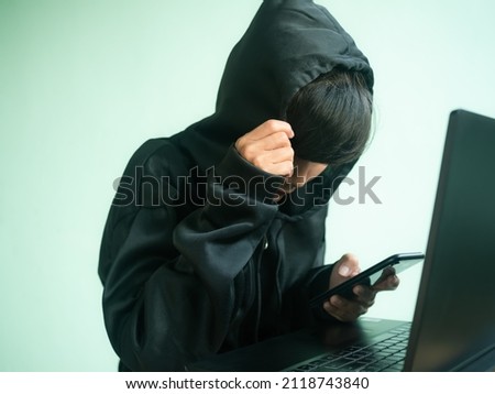 Hacker hooded use mobile phone with blur laptop computer. hack secret password code system identity theft finance.Unauthorized access to personal data. security technology thief cyber concept.