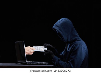 Hacker illegally receives money from the Internet. Cybercriminal hold cash or currency from laptop. Concept for computer hacker, network security, cyber attack, virus. - Powered by Shutterstock