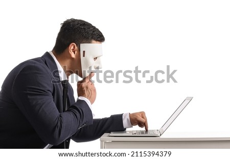 Hacker with laptop and mask at table on white background