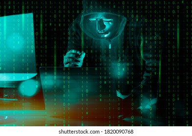 Hacker and malware concept. Dangerous Hooded hacker man using laptop with binary code digital interface.